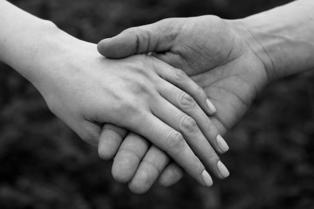 A black and white image of one hand gently holding another