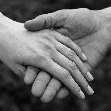 A black and white image of one hand gently holding another